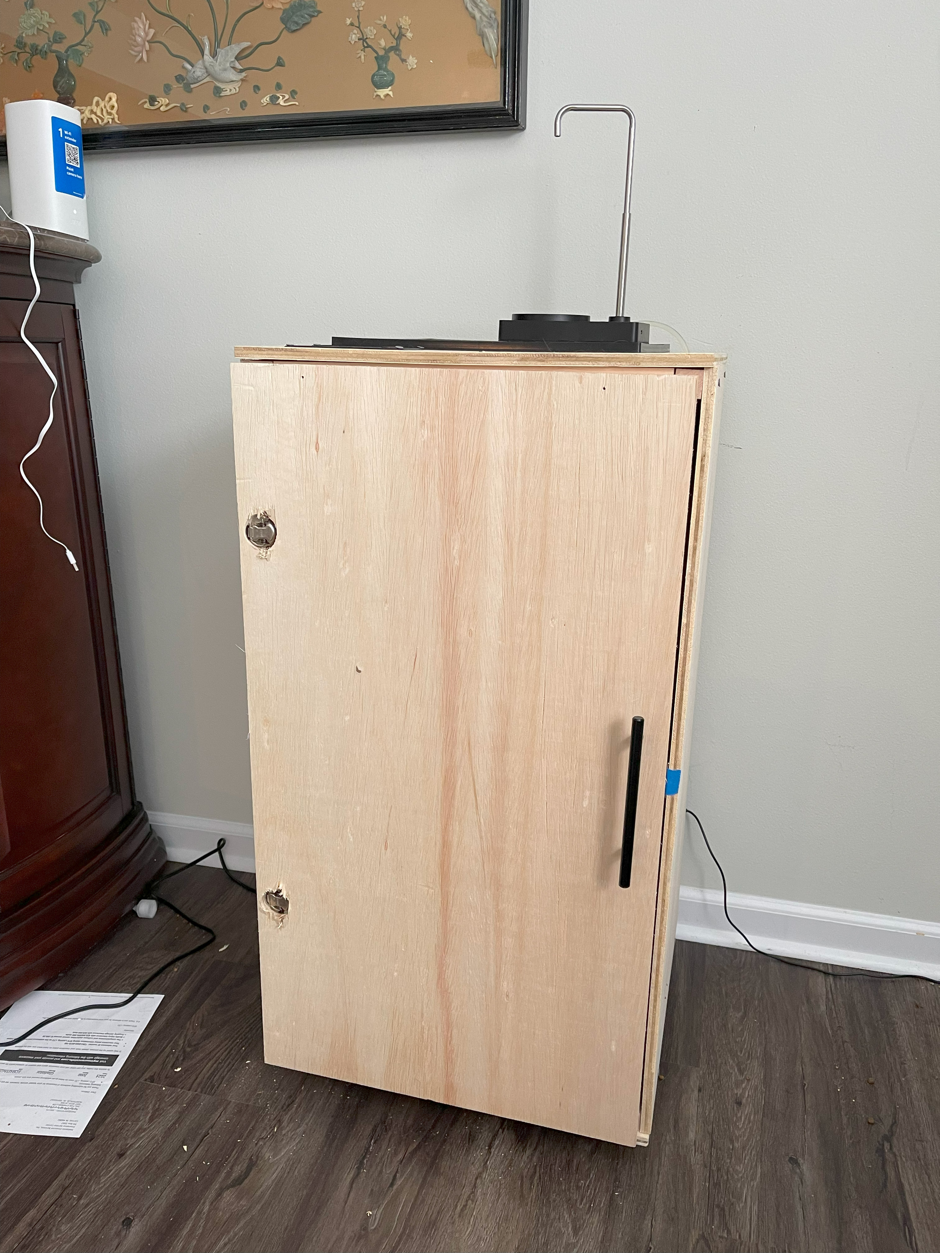 A finished cabinet with a door and water pump