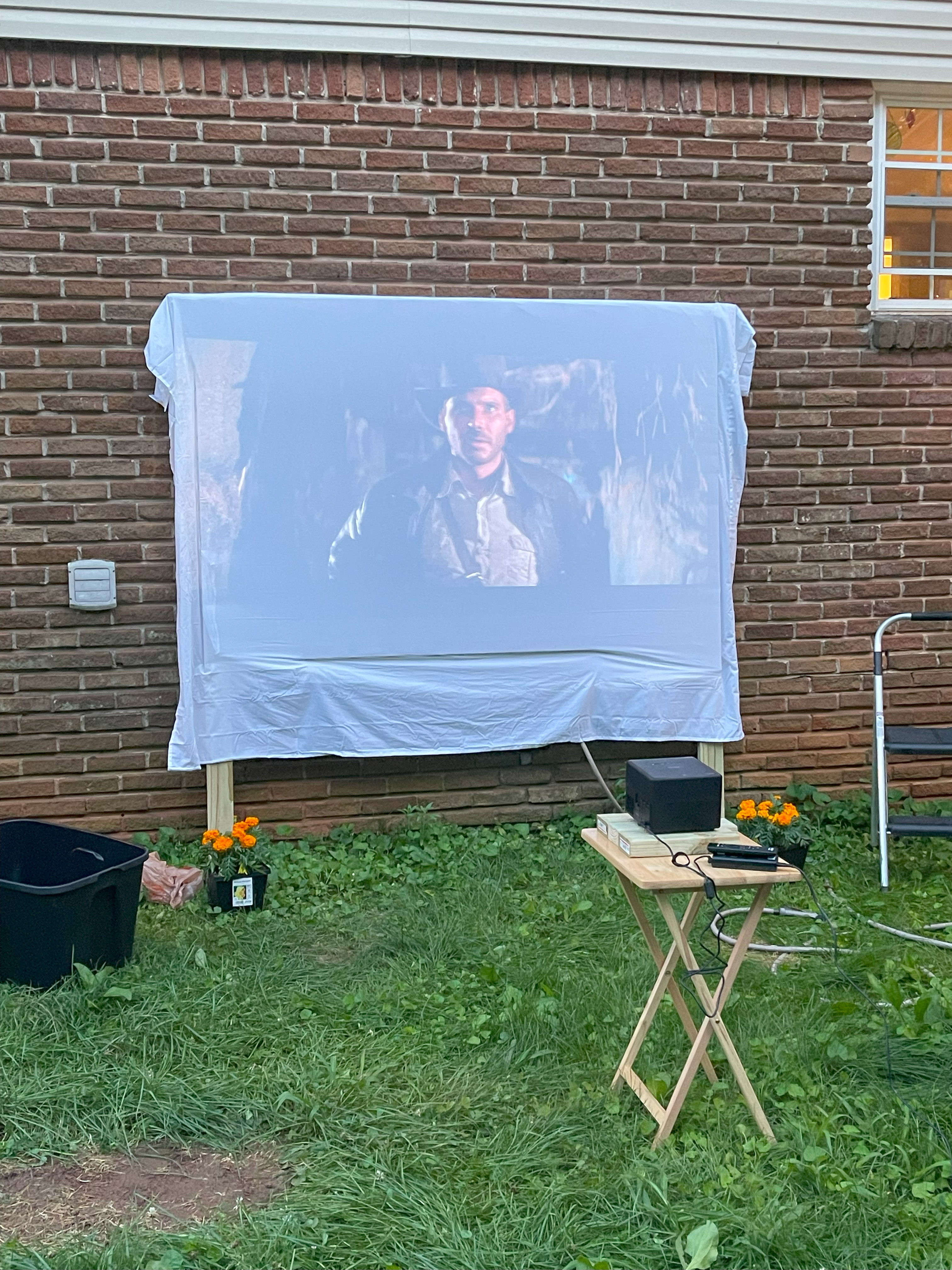 Wooden frame with a white cloth stapled around it to form a projector screen. Indiana Jones is playing on the screen