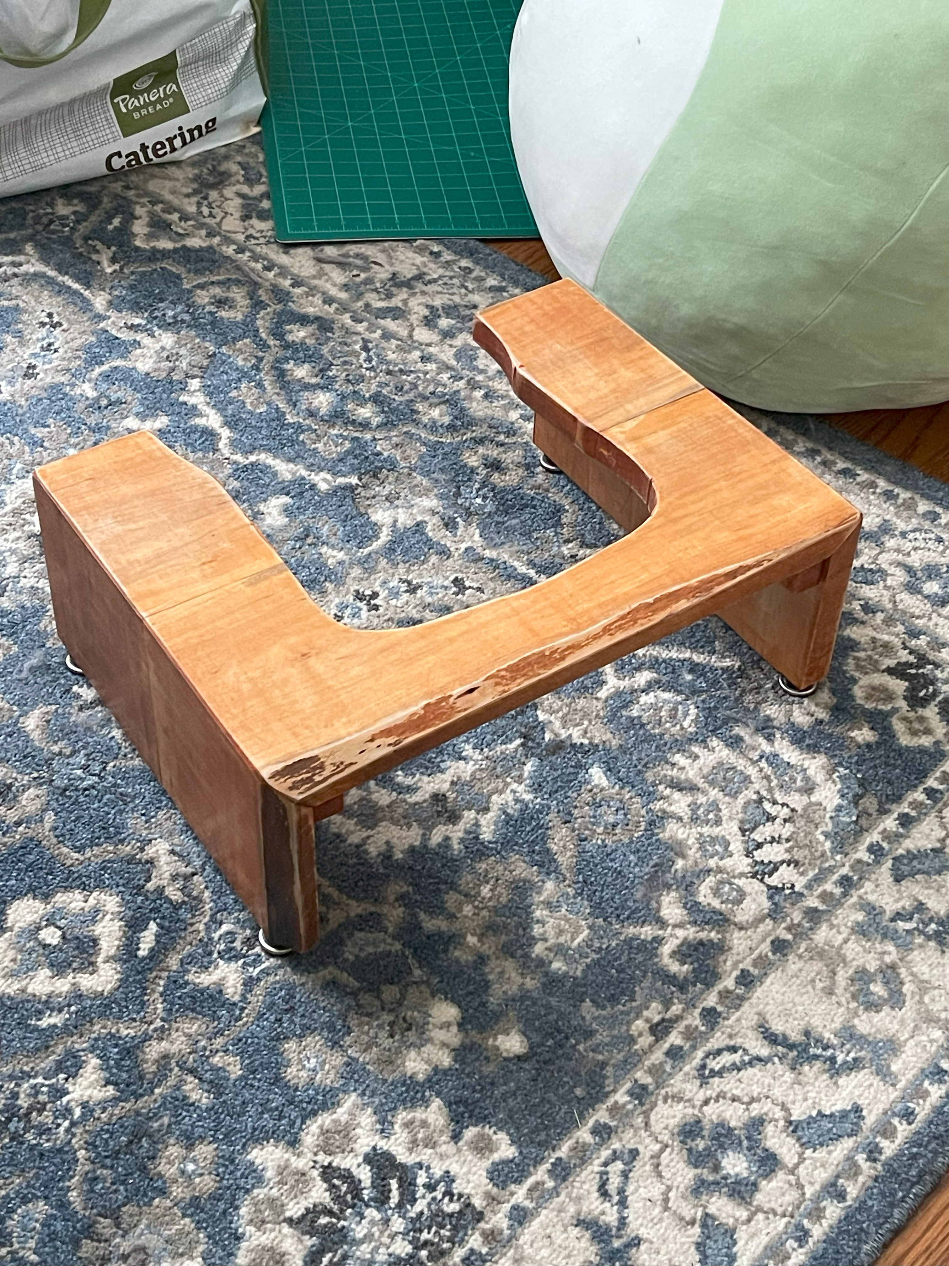 Stained maple wood stool with a hole cut out of the center for sliding under a toilet